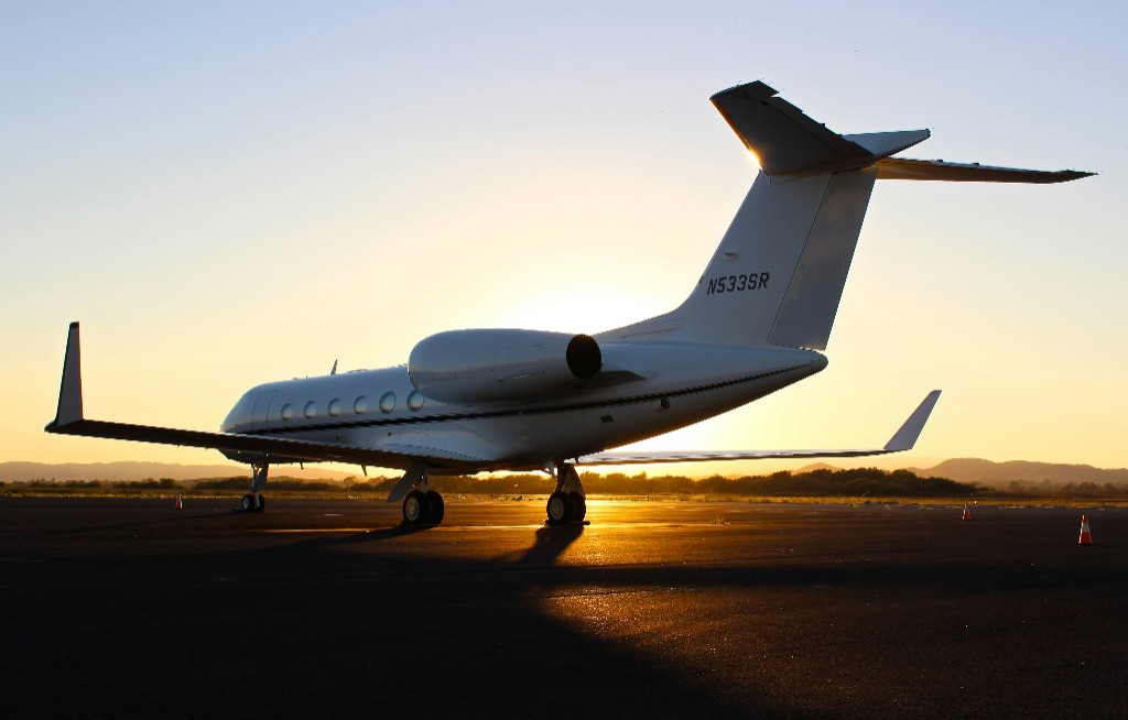 White business jet on airport tarmac at sunset with warm sky