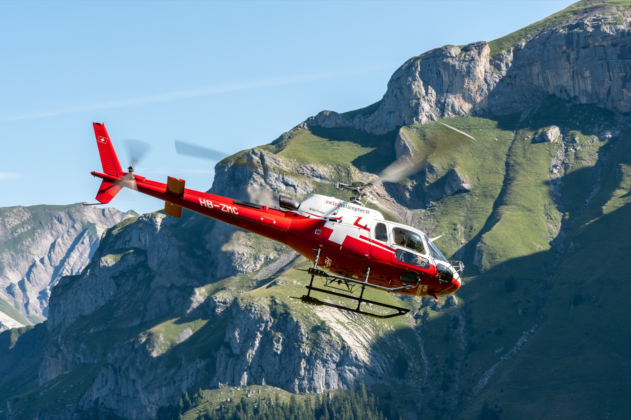 Airbus H125 helicopter in flight over alpine terrain